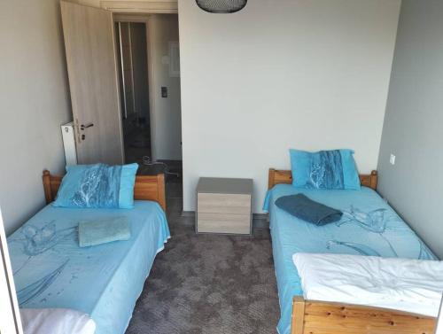 two beds in a room with blue sheets at Stelios apartment in Kastoria
