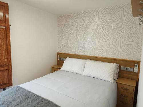 a bedroom with a white bed and a wall at casa Mariana in Villajoyosa