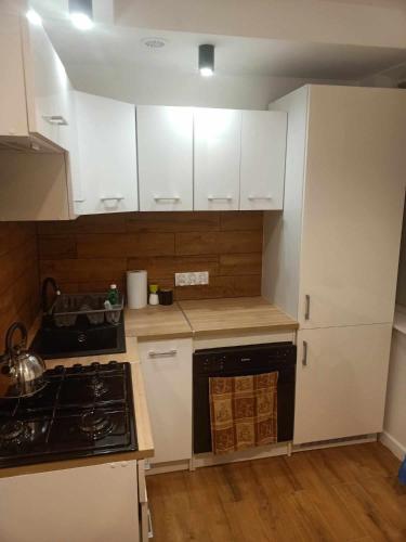 a kitchen with white cabinets and a stove top oven at Apartament na Krakowskiej w Dębicy in Dębica