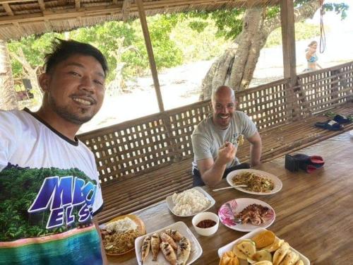 twee mannen aan een tafel met borden eten bij Ziah's Guest House in San Vicente