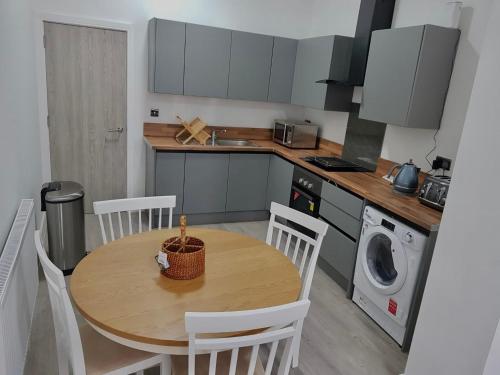 a kitchen with a wooden table and white chairs and a kitchen with a table at Kingdom apartments in Wolverhampton