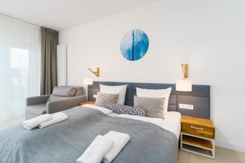 a bedroom with a large bed and a chair at Aquamarina Prima Holiday Studios by the BEACH by Noclegi Renters in Międzyzdroje