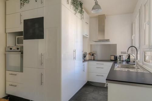 une cuisine blanche avec des armoires blanches et un évier dans l'établissement Spacieux et charmant 100m2 à 4 min de Tête d'Or, à Lyon