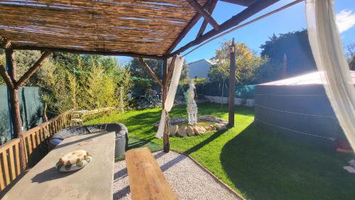 une arrière-cour avec une pergola en bois et une table dans l'établissement La Yourte, à Vinassan