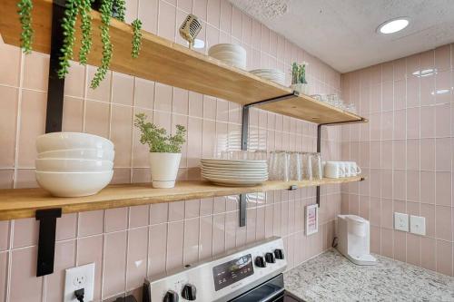 uma cozinha com paredes de azulejos cor-de-rosa e prateleiras com pratos em The Dolly-1/2 mi from the Square em Covington
