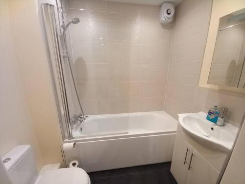 a bathroom with a tub and a toilet and a sink at Spacious 2 double bed apartment - Free Parking - Central Beeston location in Nottingham