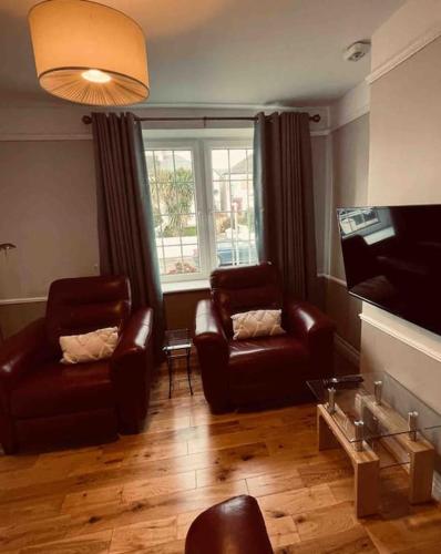 a living room with two leather chairs and a television at Beautiful House In Town in Killarney