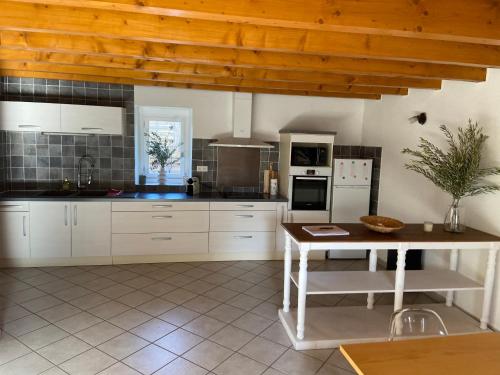 une cuisine avec des armoires blanches et un plafond en bois dans l'établissement La maison des Petits Robins, à Livron-sur-Drôme