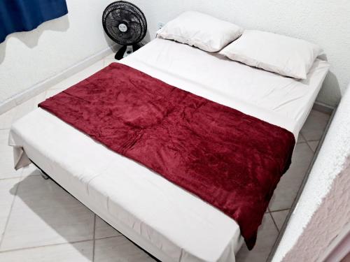 Una cama con una manta roja y blanca. en Mini Casa Aconchegante, en Saquarema