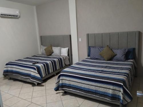 two beds sitting next to each other in a room at Tres Migueles, Departamento Alaain, familiar, comodo, cerca de la marina, zona turistica y playa in Cabo San Lucas