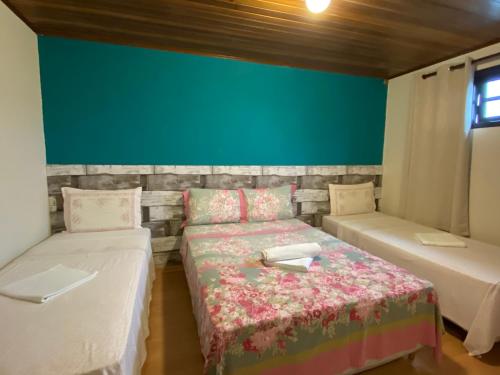 a room with two beds and a green wall at Pousada Recanto da Giovana in Campos do Jordão