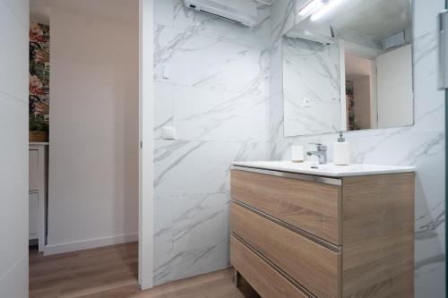 ein weißes Badezimmer mit einem Waschbecken und einem Spiegel in der Unterkunft Castelldefels Beach&Fun in Castelldefels