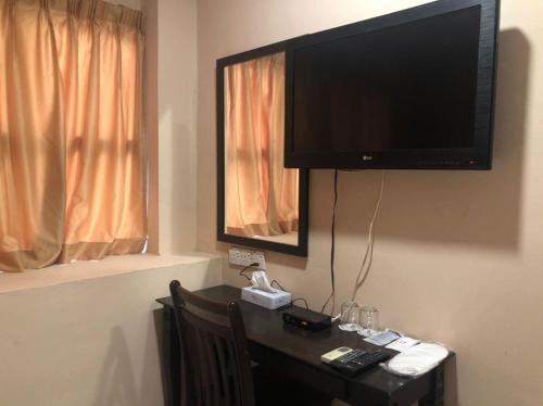 Habitación con mesa y TV en la pared. en Express Hotel, en Nilai