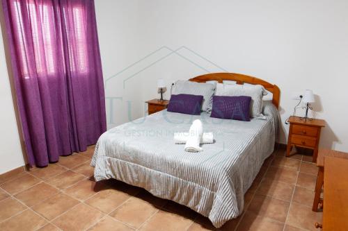 1 dormitorio con 1 cama grande y cortinas moradas en Villa Zapatilla, en Chiclana de la Frontera