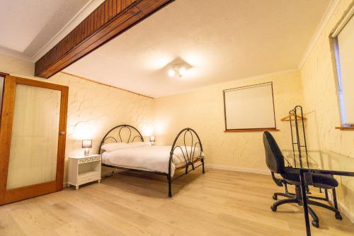 a bedroom with a bed and a desk and a chair at Cooma Guest House in Cooma