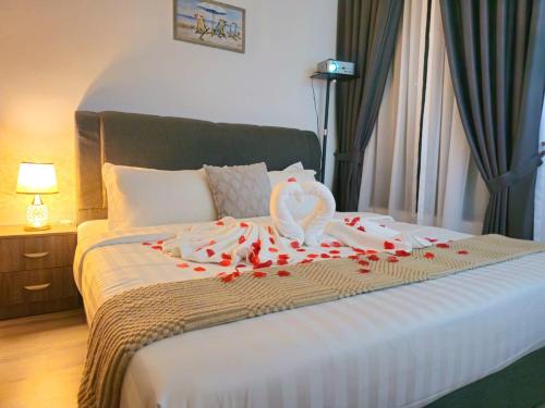 a bed with red rose petals and a swan on it at Cubic Botanical Studio 情侣体验民宿电影院的浪漫 in Kuala Lumpur