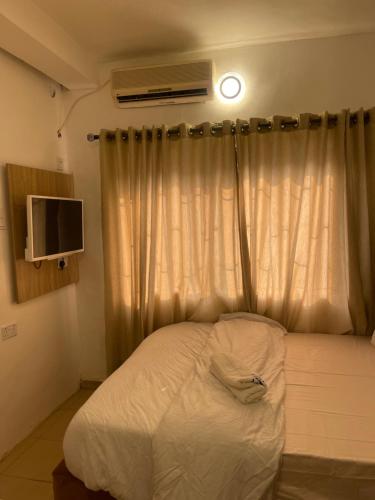 um quarto com uma cama e uma janela com uma televisão em Mph mini em Lagos