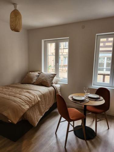 a bedroom with a bed and a table and two chairs at La météorite in Strasbourg