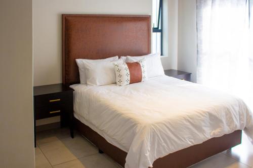 a bed with white sheets and pillows in a bedroom at 16 Elizabeth Place - Luxury Apartments, Free Wi-Fi in Midrand