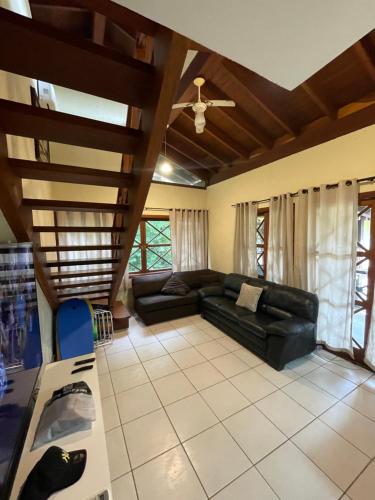 uma sala de estar com um sofá de couro preto e tectos de madeira em B12 Casa em Maresias condomínio a 50 metros da praia em Maresias