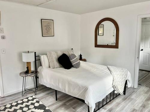 a white bedroom with a bed and a mirror at Catskills Hideaway Minutes from Hiking in Mount Tremper