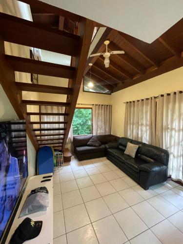 un soggiorno con divano nero e soffitto di B12 Casa em Maresias condomínio a 50 metros da praia a Maresias