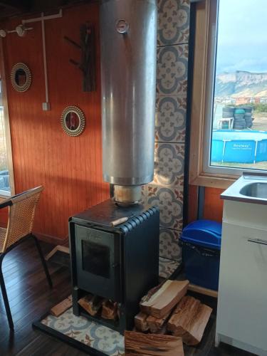 a wood stove in a kitchen with a window at Tyni house in Puerto Natales