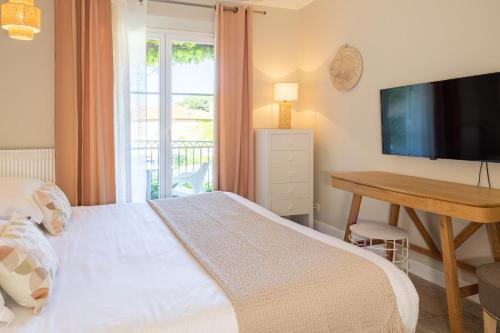 a bedroom with a bed and a desk and a television at Hotel des Lices in Saint-Tropez