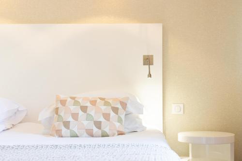 a bedroom with a bed with a pillow and a table at Hotel des Lices in Saint-Tropez