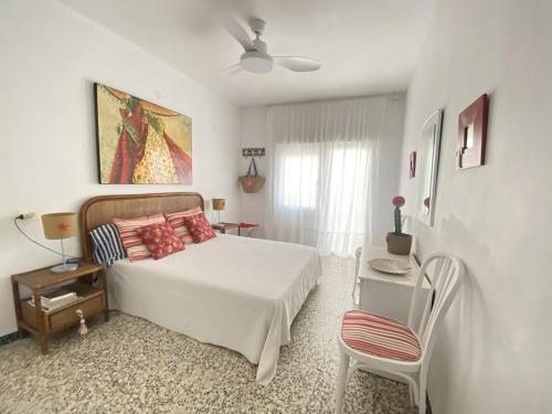 een witte slaapkamer met een bed en een stoel bij Apartamento familiar a 200m de la playa in Alcossebre