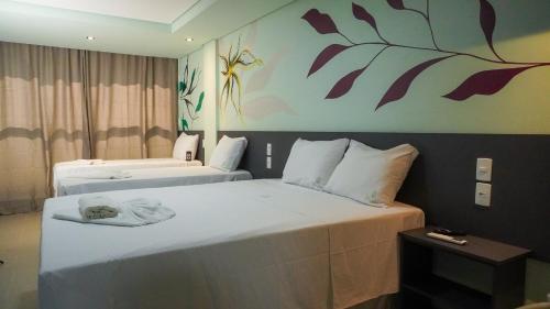 una camera d'albergo con due letti e un dipinto sul muro di Pousada Flor de Magnólia a Porto De Galinhas