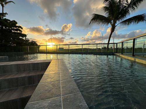 a swimming pool with a sunset in the background at Pousada Flor de Magnólia in Porto De Galinhas