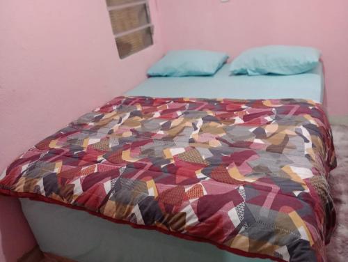 a bed with a colorful quilt on top of it at Apartamento Acochegante in Manaus