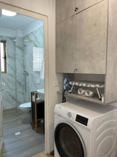 a washing machine in a bathroom with a shower at Sunny City Center Apartment in Lezhë