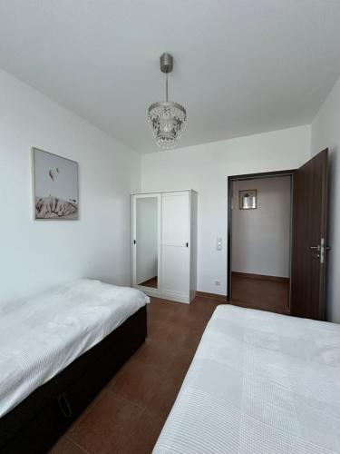 een witte slaapkamer met 2 bedden en een kroonluchter bij Temporalis Unterkunft in Langerwehe