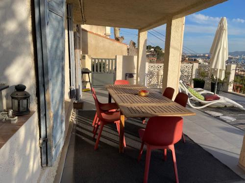y balcón con mesa y sillas de madera. en Superbe terrasse avec vue panoramique sur la mer, en Marsella