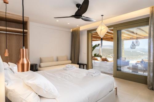 a bedroom with a large white bed and a balcony at Panormos Bay Suites Luxury Resort in Mykonos