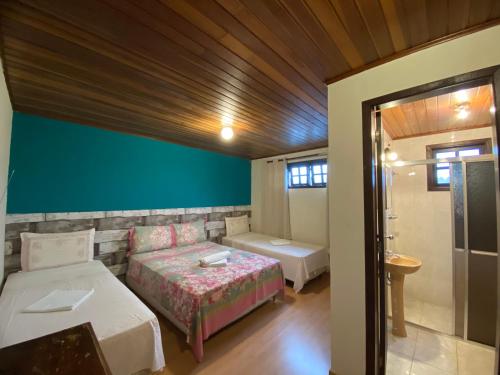 a bedroom with two beds and a green wall at Pousada Recanto da Giovana in Campos do Jordão