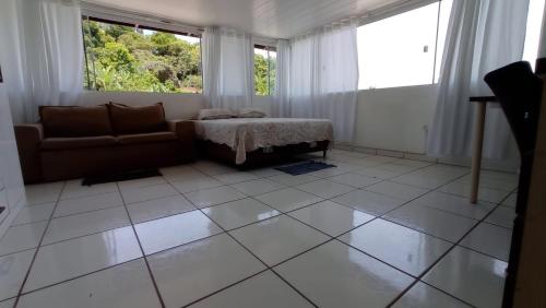 a living room with a couch and some windows at Pousada Alto da Maroca in São Francisco do Sul