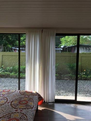 a bedroom with a bed and sliding glass doors at Casa del Árbol in Quepos