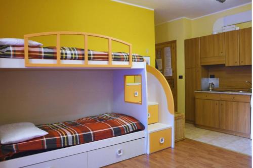 a bunk bed in a room with a kitchen at 5 Minuti da Monterosa Ski, Piccolo Cottage in Gressoney-la-Trinité