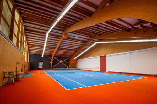 a tennis court in a large room with an orange floor at Vital- und Wellnesshotel Albblick in Waldachtal
