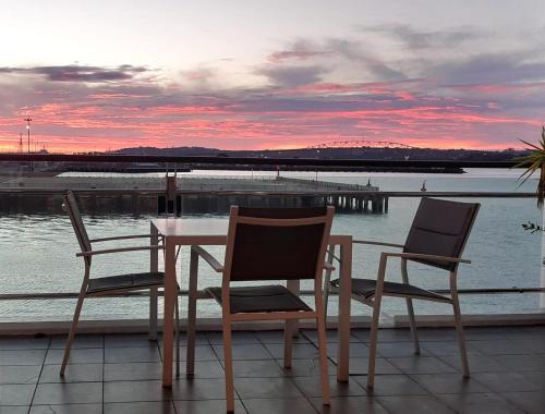 a table and chairs on a balcony with a view of the water at Life on Water- Princes Wharf apartment with fabulous views in Auckland