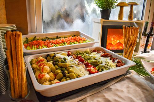 two trays of different types of vegetables next to a fireplace at Vital- und Wellnesshotel Albblick in Waldachtal