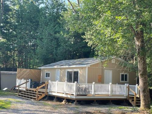 a mobile home with a porch and a tree at Sandy Shadow in Kawartha Lakes