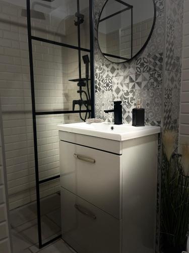 a bathroom with a white sink and a mirror at ROMAN Residence Apartment in Borşa