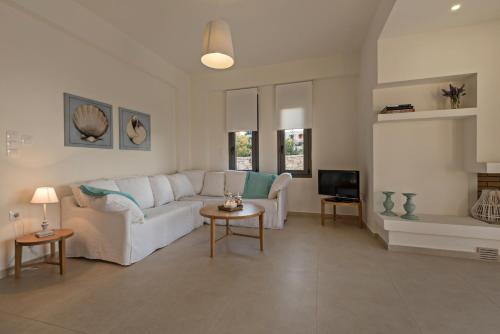 a living room with a white couch and a tv at Lygaries Villas in Panormos Rethymno