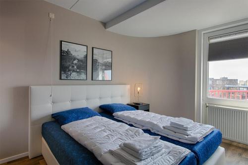 1 dormitorio con 2 camas con sábanas azules y ventana en Zuiderzeestate 35, prachtig appartement aan het IJsselmeer en Makkum
