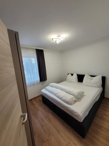 een slaapkamer met een bed met witte lakens en een raam bij Apartment an der Donau in Krumnussbaum