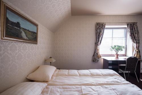 a bedroom with a bed and a desk and a window at Hotel Folwark in Zgierz